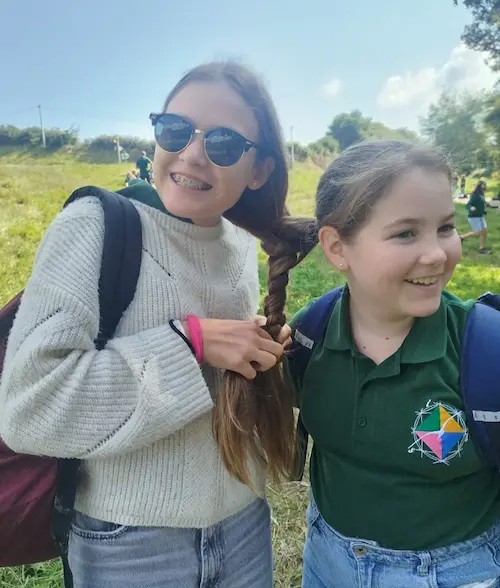 Deux jeunes filles de 5ème se tressent leurs cheveux ensemble ce qui illustre la cohésion du cycle des 5èmes